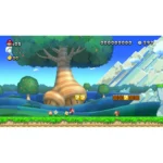 Mario runs through a bright side-scrolling level with green grass, flowers, and a large striped tree in the background; two yellow question blocks and brick blocks hover above the ground, with a goomba on the right and a blue sky backdrop.