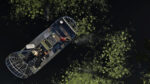 Aerial view of a small boat with people cruising through a dark waterway covered in green lily pads and vegetation floaters.