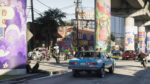 Colorful urban street scene with mural-covered columns under a highway, a blue vintage car driving by, and people on motorcycles.