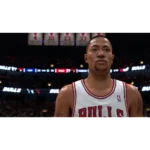 Close-up of a basketball player in a Chicago Bulls jersey on a dimly lit court, arena crowd in the background with banners overhead.