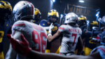 203e567e-54b0-4770-a41e-b4e842ce60b1 - Video Game Depot Football players in helmets form a tight huddle in a dim tunnel, preparing for kickoff.