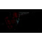 Close-up of a red-tinged, stitched mask emerging from deep shadows in a dark scene