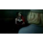 51lKNlRpG8L_SL1500___661561781803212 - Video Game Depot Moody scene of a woman in a black strapless dress and red scarf looking at her reflection in a dim elevator mirror; a blurred person is in the foreground.