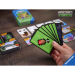 81A2wdWP3sL_AC_SL1500___106821785339826 - Video Game Depot Person holds a fan of green Minecraft Explorers cards on a wooden table with the game box and cards laid out in the background.