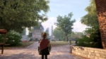 8f0d9e71-3069-4b63-b6c6-cffd0a47bc4e - Video Game Depot Third-person view of a knightly character with a red shield standing on a stone path in a sunny medieval town square, leading toward a castle gate with domed towers in the distance.
