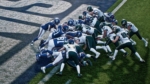 9b465c03-3487-43a7-b6bc-d256255668f3 - Video Game Depot Football players in blue and white jerseys collide at the goal line during a scrum on a green field.