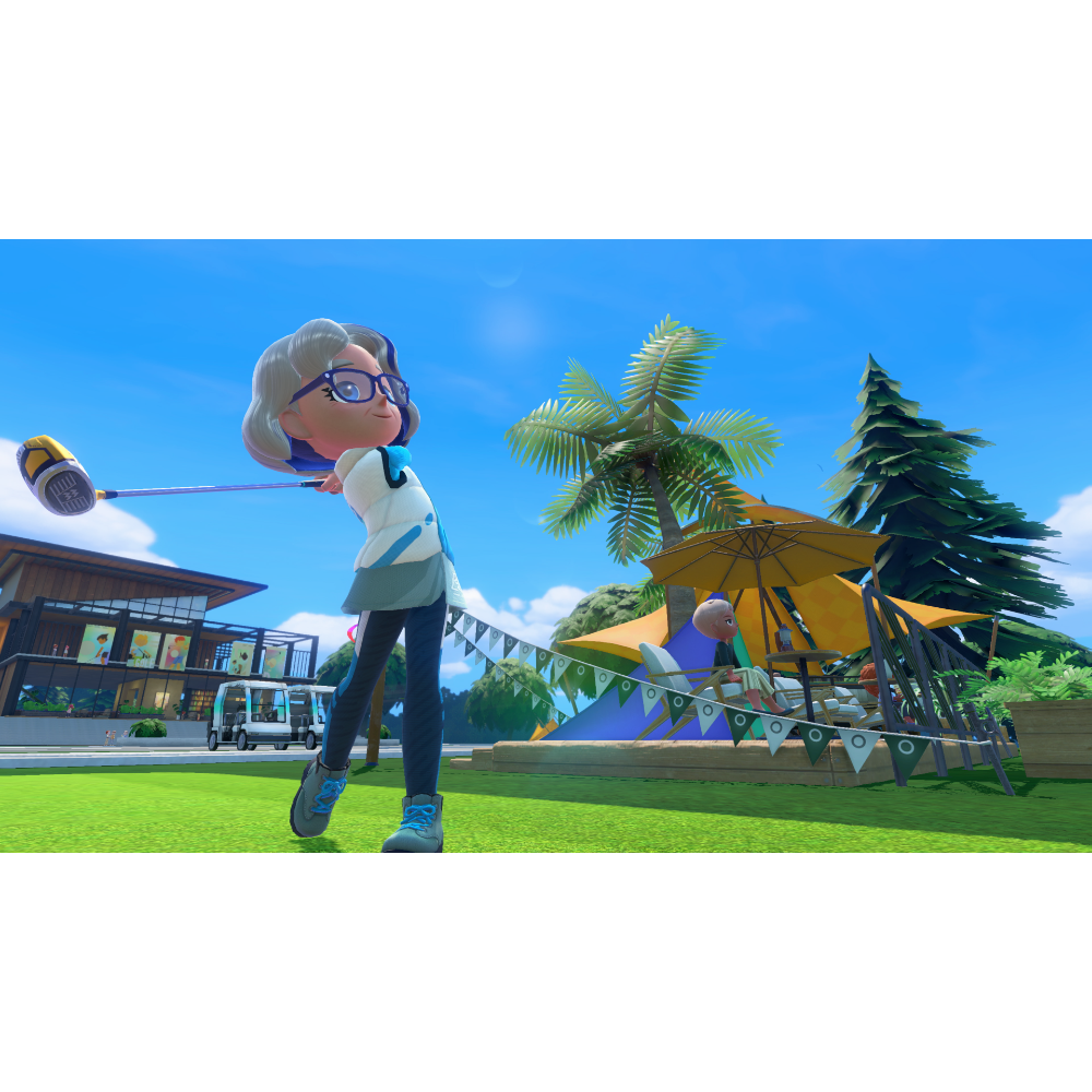 Older woman with glasses swings a golf club in a sunny park festival, with tents and palm trees in the background.