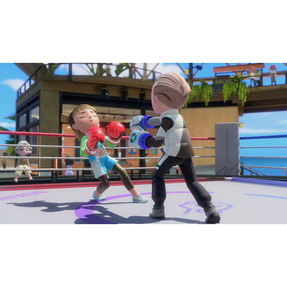 Young girl in boxing attire throws a punch at a boy as they spar in a bright outdoor boxing ring with ropes and spectators nearby.