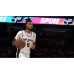 Basketball player in Spurs white jersey with number 5 dribbles a ball on court as fans watch from stands.