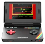 SpectrumImage2 - Video Game Depot Portable retro handheld game console with a large screen showing a pixel-art platformer; red D-pad, color buttons (red, yellow, green, cyan) and a rainbow stripe on the body.