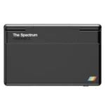 SpectrumImage5 - Video Game Depot Front view of The Spectrum handheld device, black with a textured top and a small rainbow stripe logo in the bottom-right corner