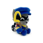 Soft plush raccoon character wearing a blue cap and yellow scarf, sitting with a yellow curved prop in its paw.