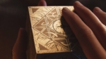 cd3ab72a-76f0-4ace-83f1-c9f85e07b8b5 - Video Game Depot Close-up of a decorative metal cube with geometric triangular panels, held between two hands.